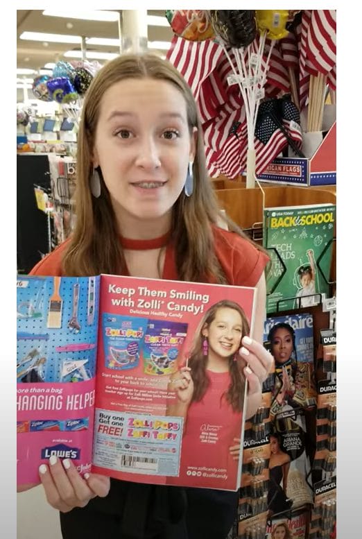 Alina Morse, holding a magazine featuring zolli candy, link opens in a new tab.